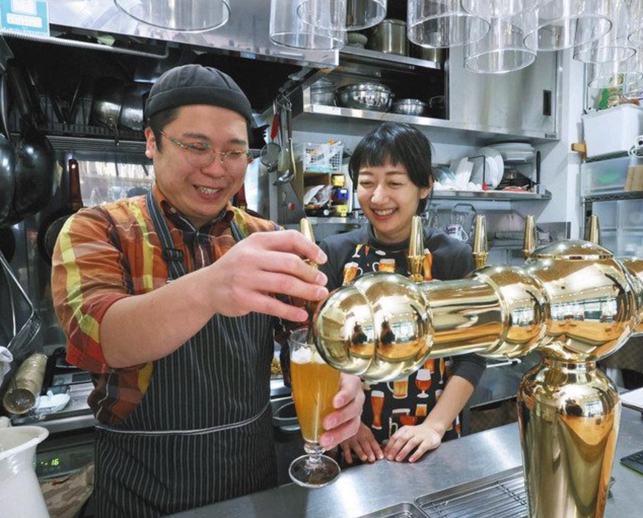 併設する醸造所で作った生ビールを注ぐ後藤健朗さん（左）と妻の由紀子さん＝世田谷区で