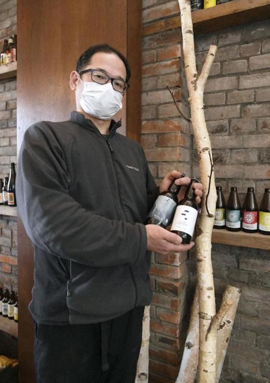 赤れんが倉庫のレストランで、シラカバの樹液が入ったビールを持つ「美深白樺ブルワリー」社長の高橋克尚さん＝北海道美深町で